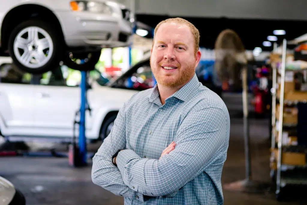 Portrait of automotive technician smiling inside repair garage.